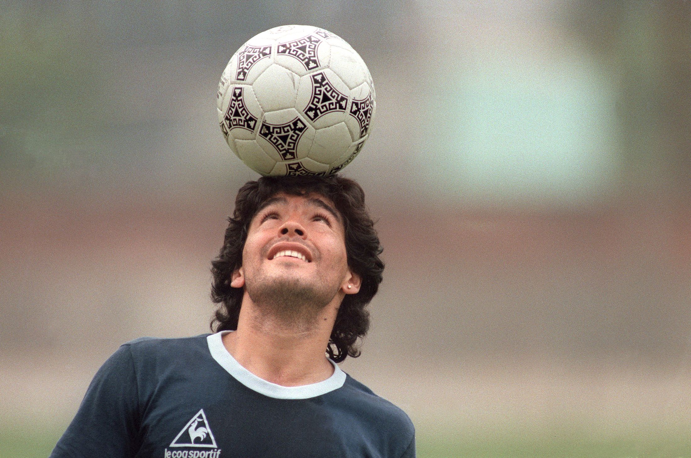 Аргентинский футболист Диего Марадона  держит футбольный мяч на голове, уходя с тренировочного поля после тренировки национального отбора 22 мая 1986 года в Мехико. 