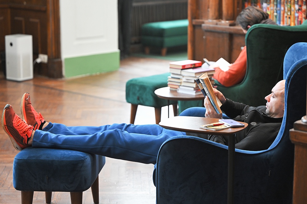 мужчина полулежит в кресле и читает книгу