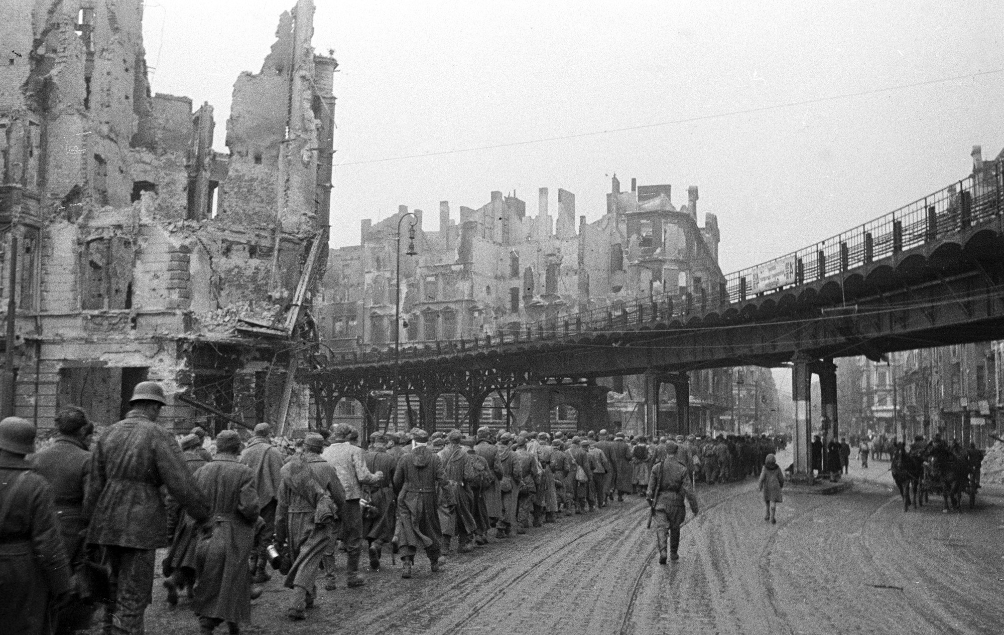 Колонна пленных гитлеровцев конвоируется на сборный пункт по разрушенным улицам Берлина. Май 1945 года.