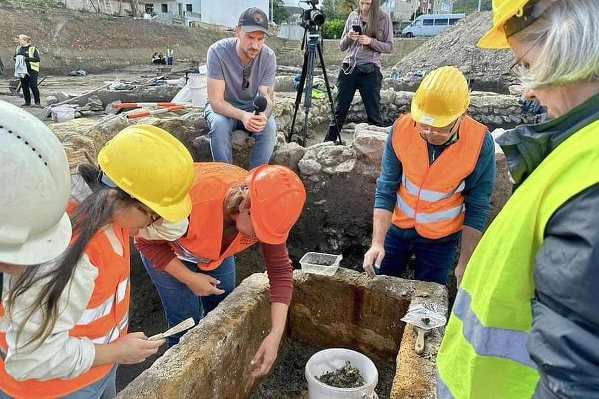 После снятия крышки археологи обнаружили неповрежденный скелет молодой женщины. Вокруг лежали погребальные дары - два стеклянных сосуда, бронзовые фигурки и 140 монет. 