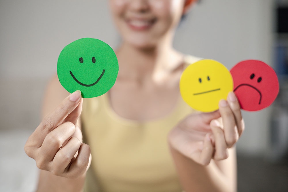 Женщина держит в руках бумажные стикеры с улыбками