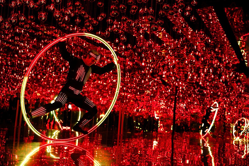 Актер со светящимся хулахупом изображал одновременно цирк и городскую суету. 