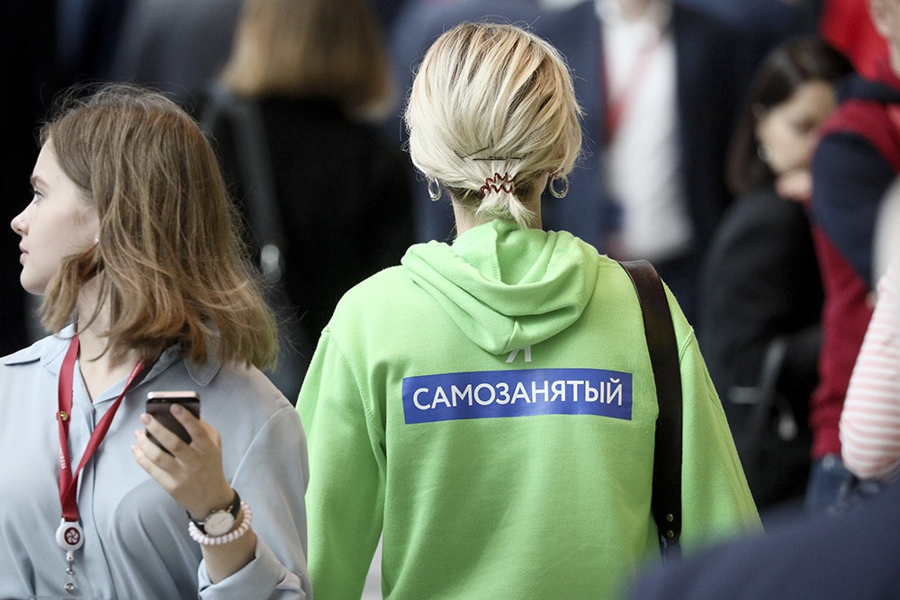 Получение ипотеки для самозанятого гражданина перестало быть исключительной ситуацией. Девушка на форуме в зеленой кофте и надпись на одежде "Самозанятый"