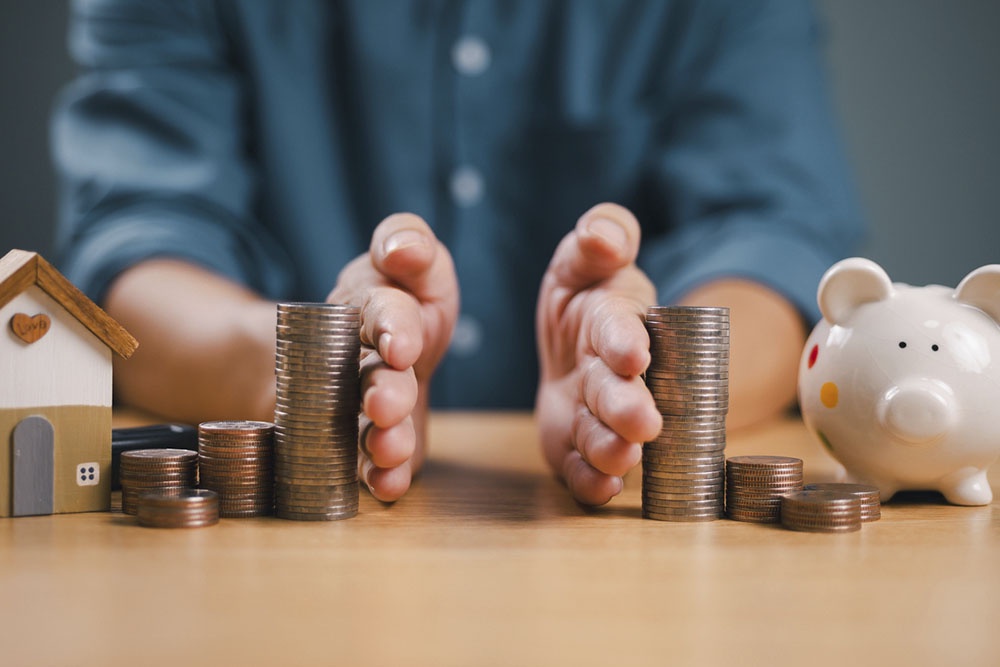 Человек разделяет монеты на две равные части, планирует на какие потребности потратить финансы