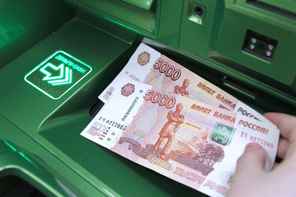 Человек снимает наличные деньги в банкомате