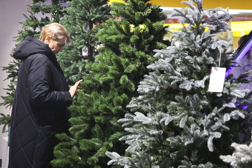 Женщина выбирает искусственную елку