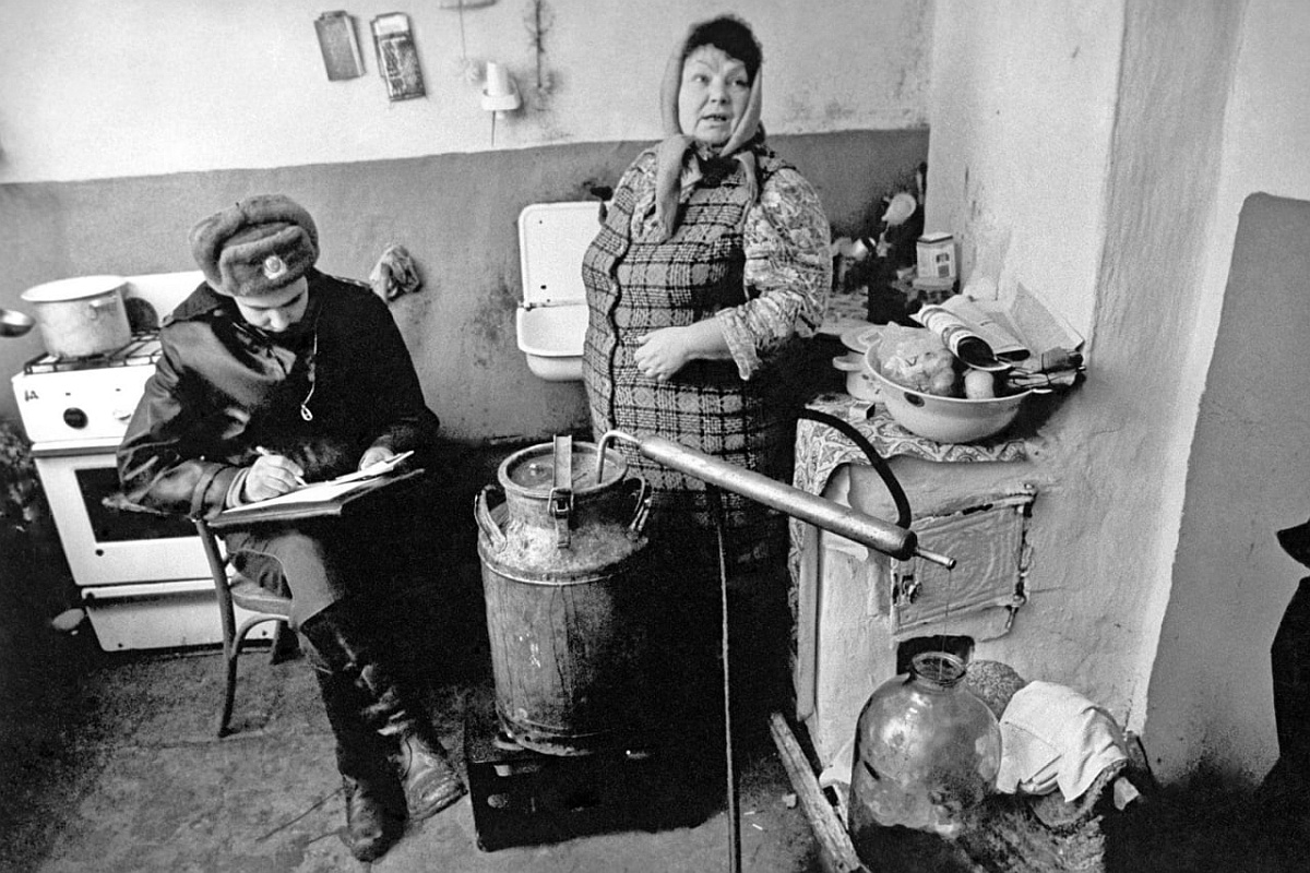 Рейд по борьбе с самогоноварением. На снимке: участковый инспектор составляет протокол в доме самогонщицы. 1987 год. Рейд по борьбе с самогоноварением. На снимке: участковый инспектор составляет протокол в доме самогонщицы. 1987 год.