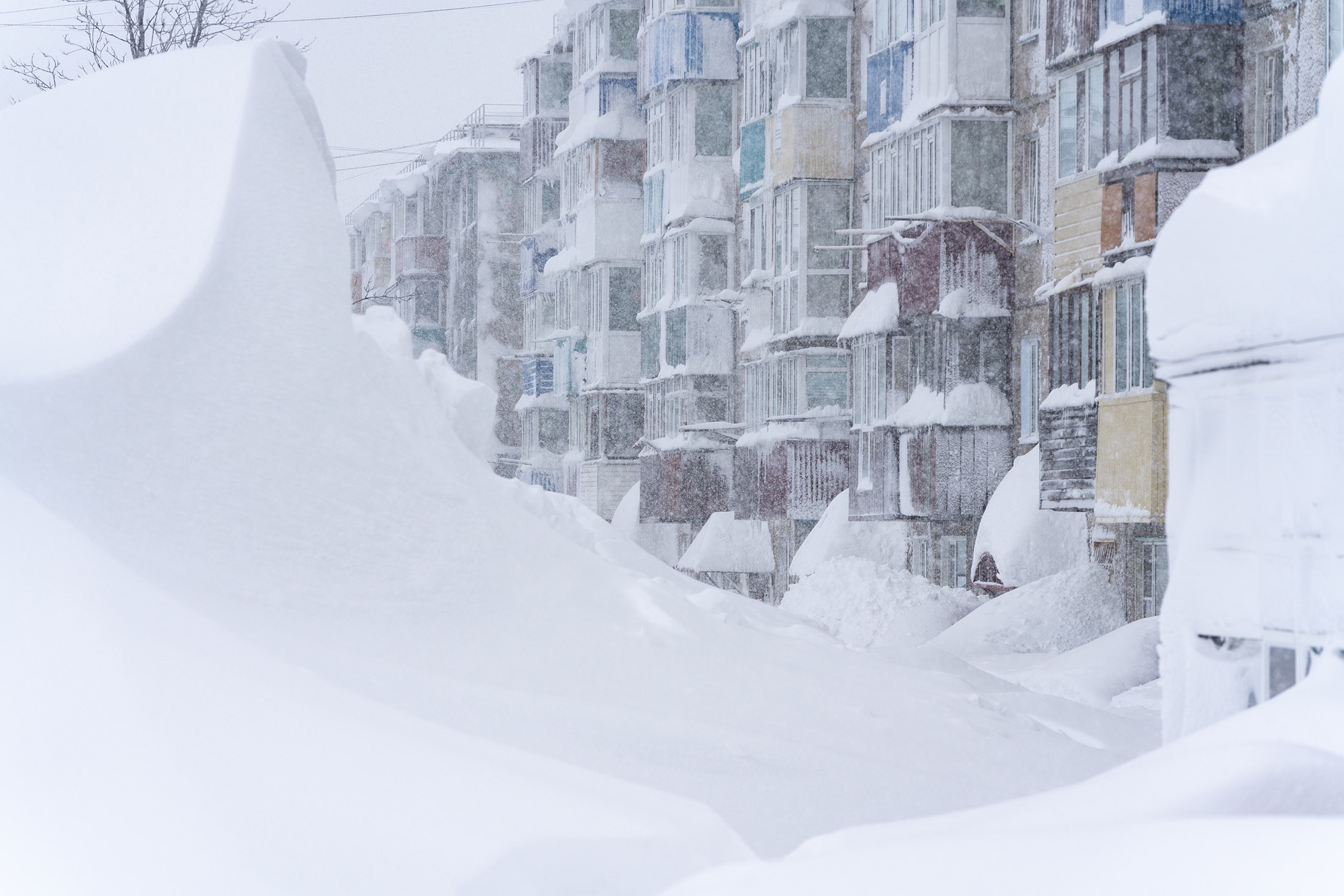 Высота сугробов достигает окон 2, 3 и даже 4 этажей жилых домов.