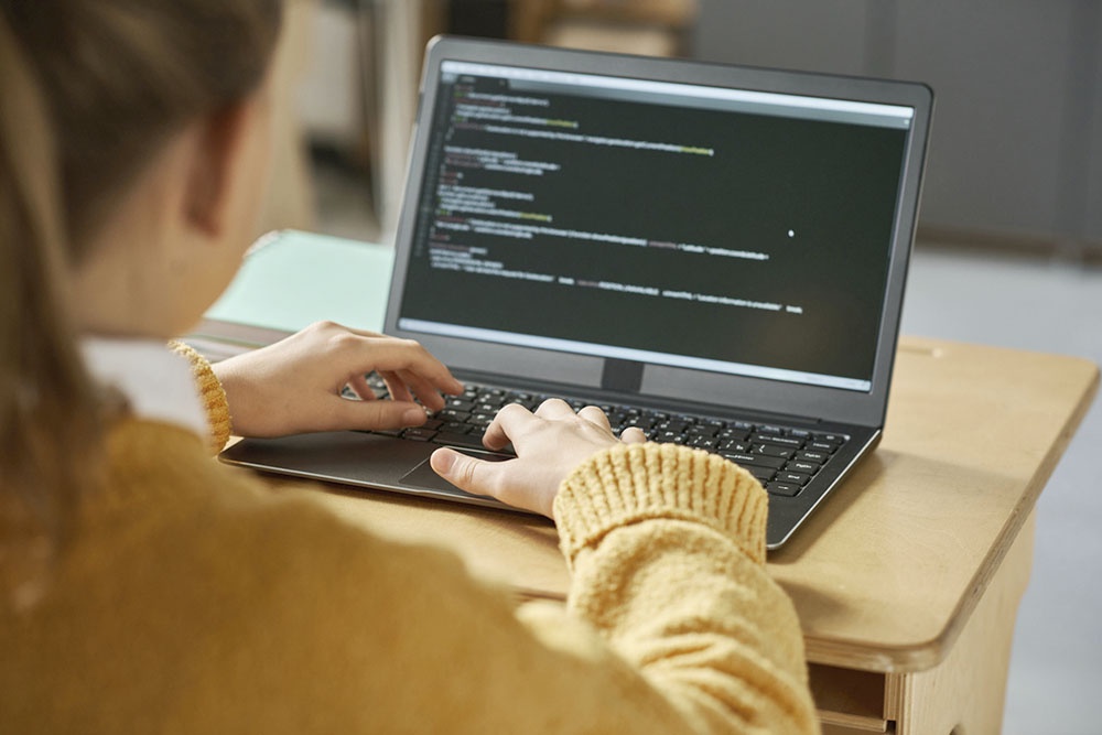 Оптимально начинать знакомство с миром программирования примерно с 8-10 лет. Однако многие современные курсы предлагают занятия даже для дошкольников, начиная с 5-6 лет. Школьница увлеченно работает за компьютером, изучая программирование.