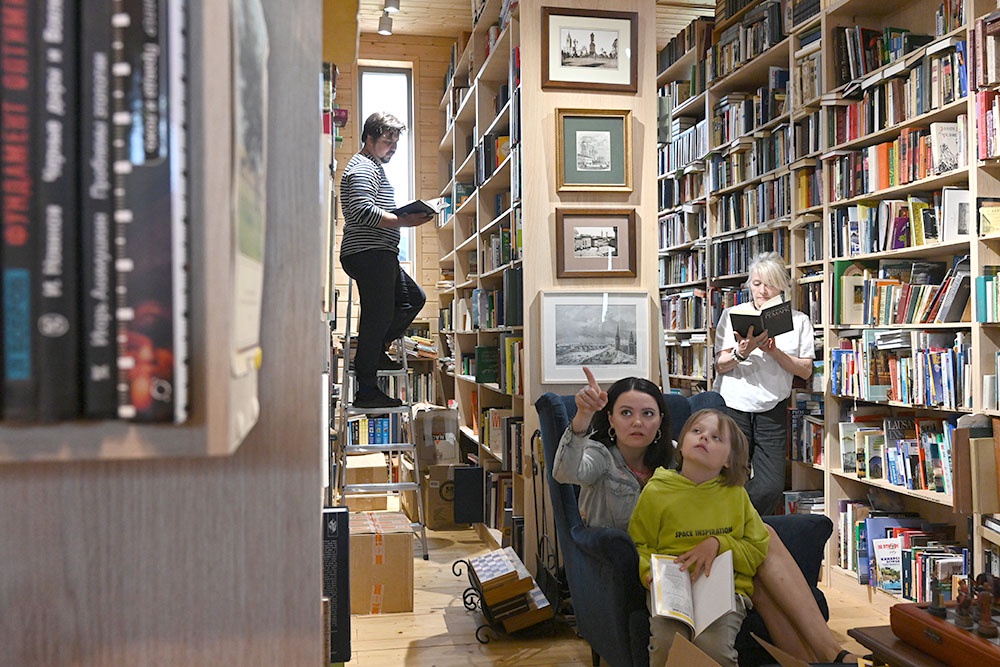 Общий вид зала библиотеки в Доме культуры села Веськово: посетители выбирают книги у стеллажей.