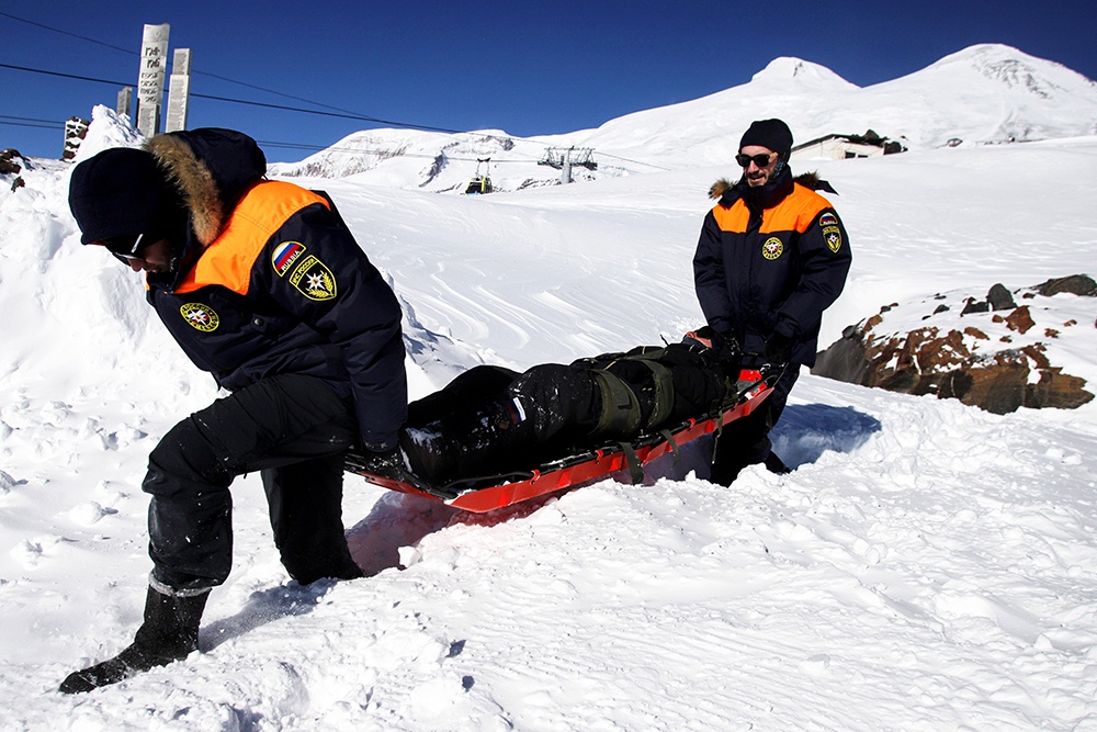 На склонах дежурят спасатели, они спускают пострадавшего на специальных носилках, оказывают первую помощь и передают медикам.