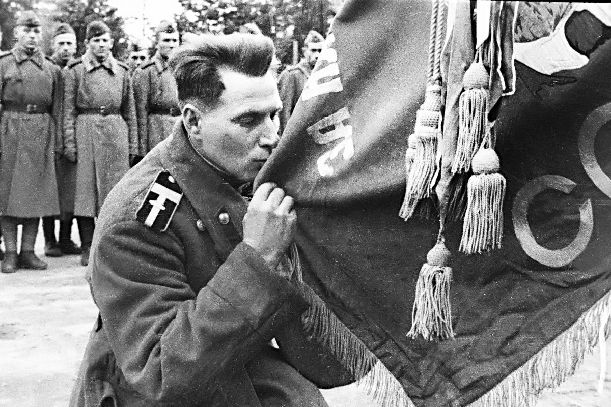 Боец Красной армии перед демобилизацией прощается со знаменем своей части.