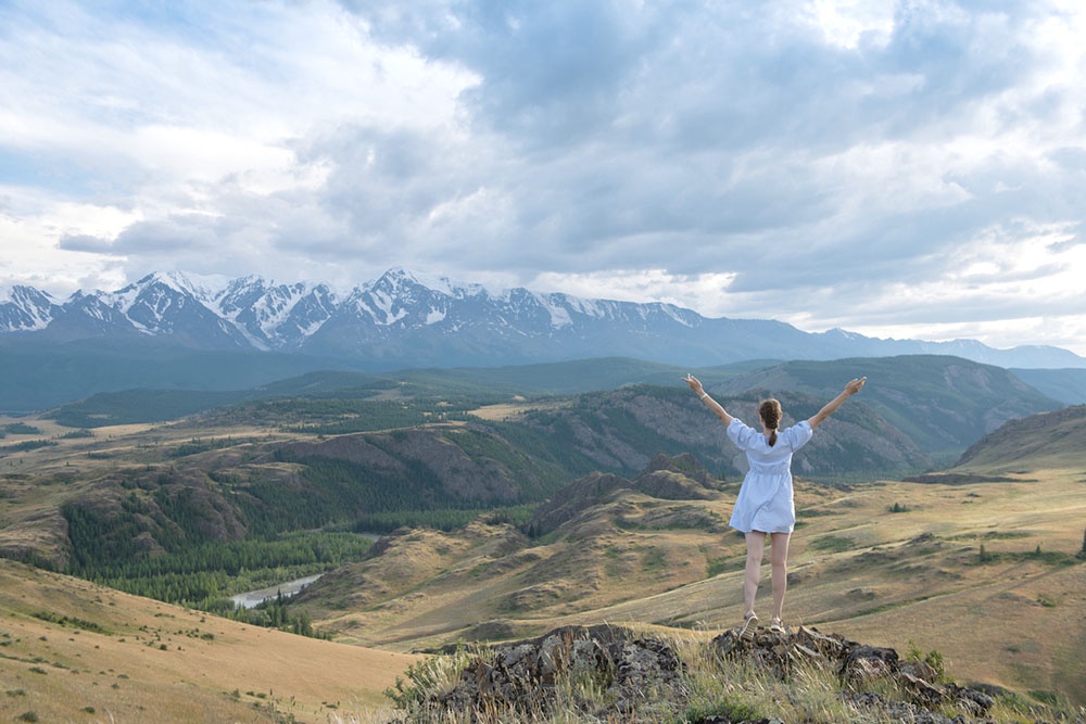 Экологические рейтинги России 2026 года: где дышится легче всего? Города и регионы - лидеры по чистоте воздуха и регионы с высокими экологическими показателями. Женщина в летних горах Алтая.