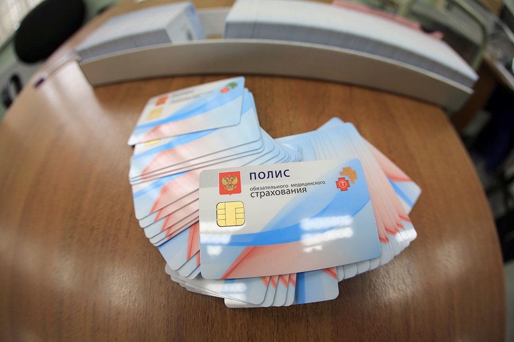 Полис ОМС - обязательное медицинское страхование, гарантирующее бесплатную помощь по всей России. ДМС - добровольная страховка, расширяющая возможности и комфорт лечения. Стопка напечатанных ОМС полисов.