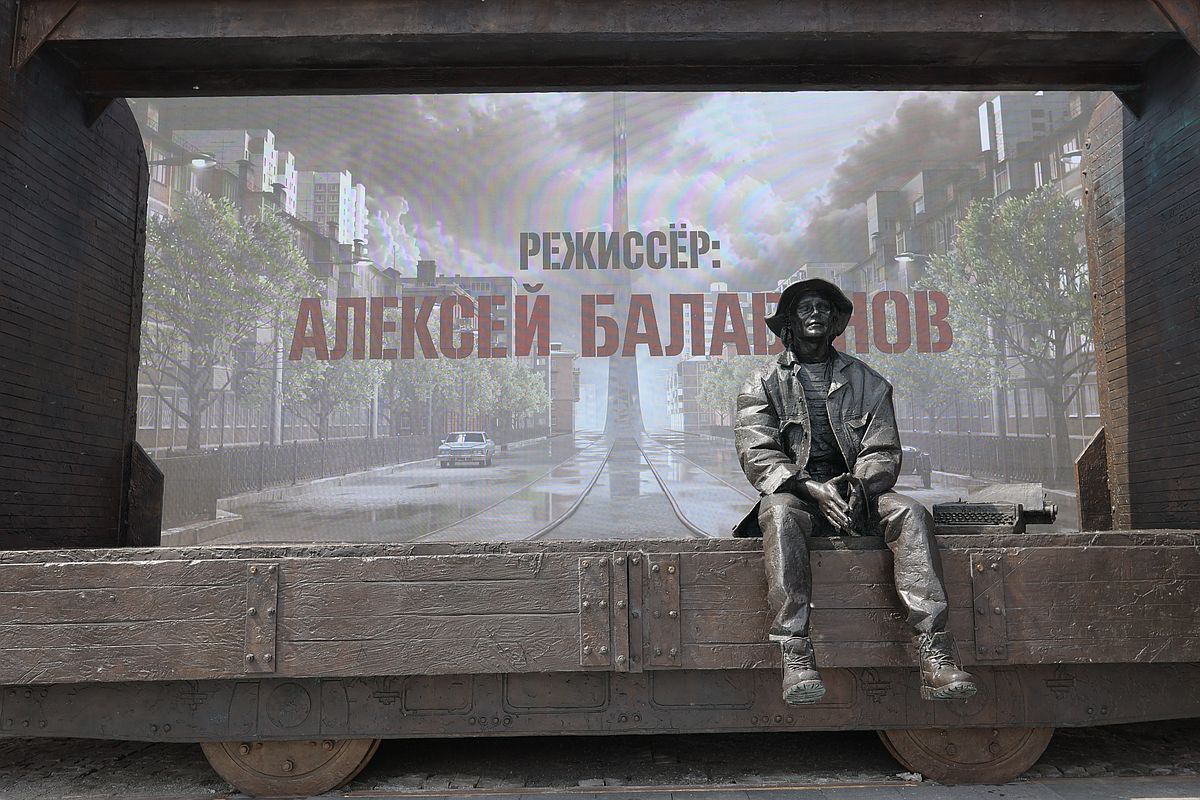 Балабанов сидит в вагоне, фальш‑рельсы под ним соединены с действующей трамвайной линией.
