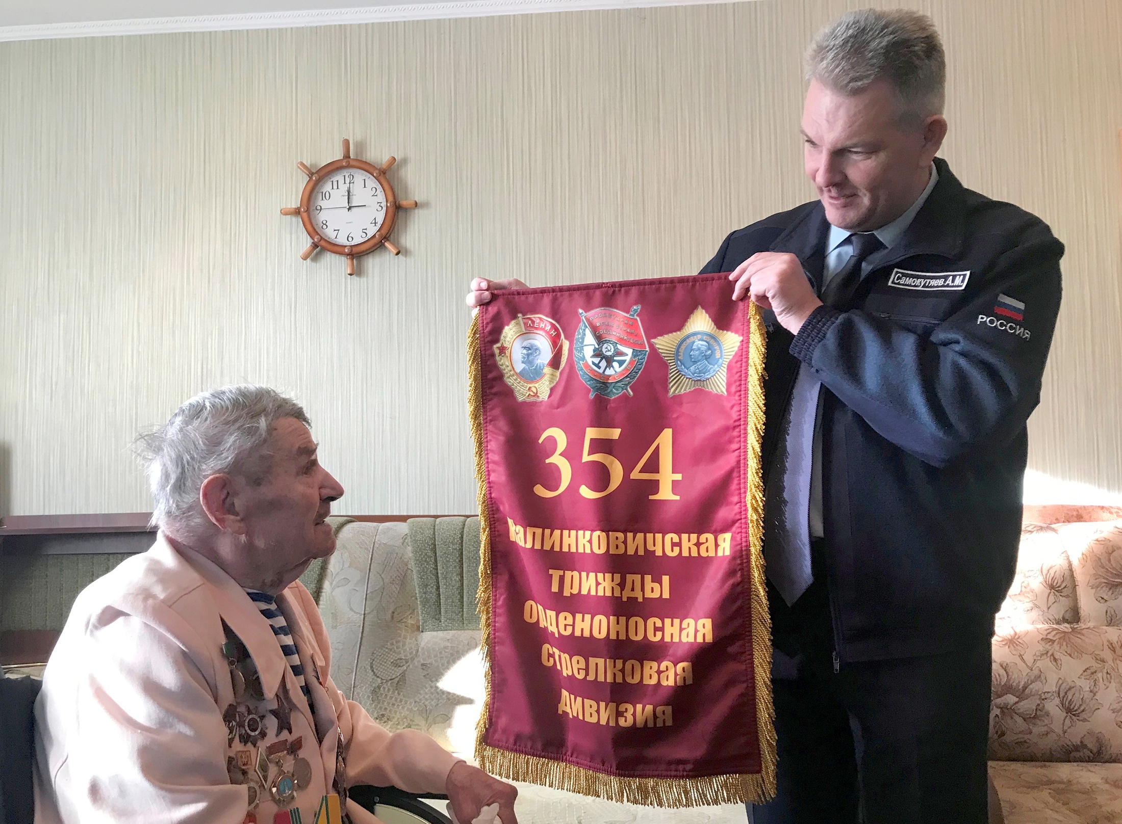 1 декабря 2022 года, поселок Рамзай Пензенской области. Александр Самокутяев передает А.К. Дручкову побывавший в космосе штандарт Совета ветеранов 354-й стрелковой дивизии.