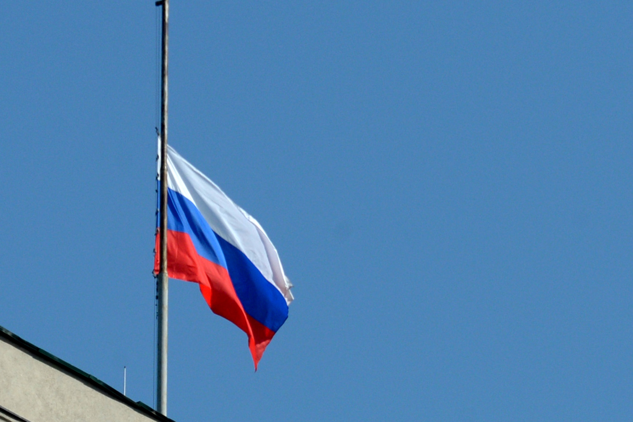 Государственный флаг России приспущен над зданием.