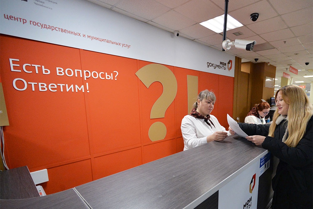 Женщина получает консультацию на стойке администрации в МФЦ