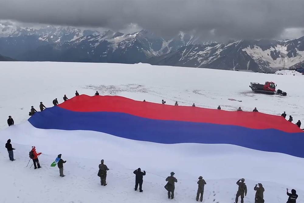 Огромное полотно российского флага и участников акции пришлось поднимать с помощью ратраков Огромное полотно российского флага и участников акции пришлось поднимать с помощью ратраков