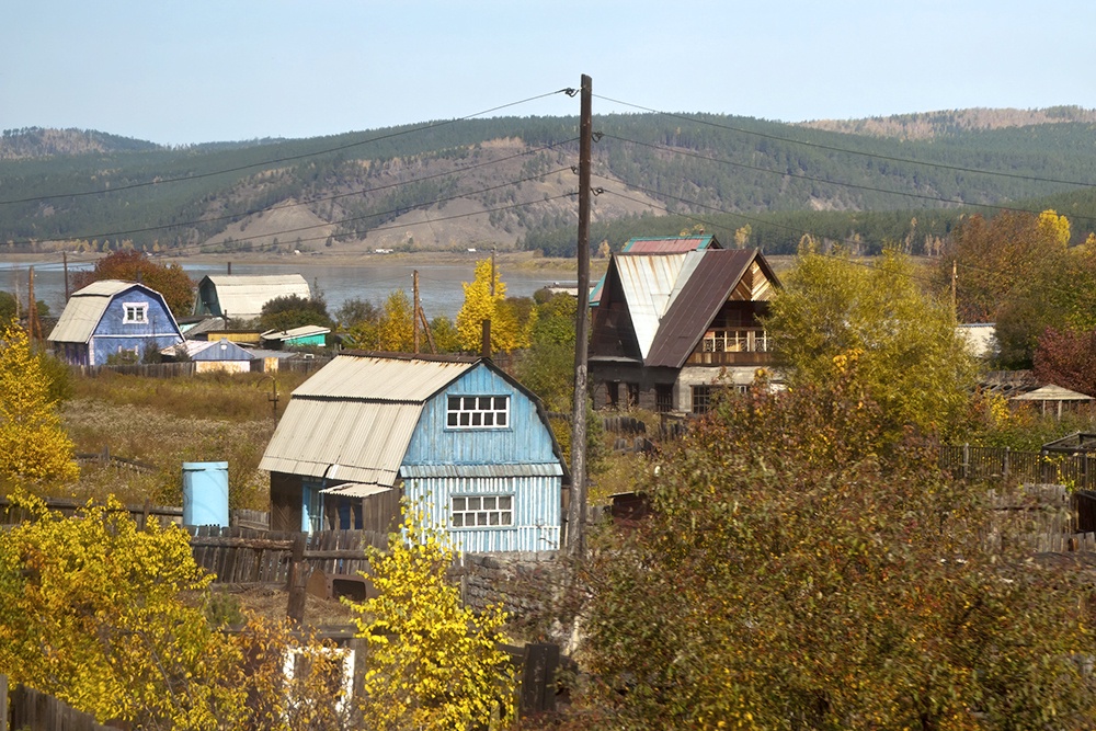 Подготовка дачи к зиме: слить воду из баков и труб, очистить печь и дымоход, убрать сухую траву и горючий мусор возле построек. Вид на СНТ в России в середине октября.