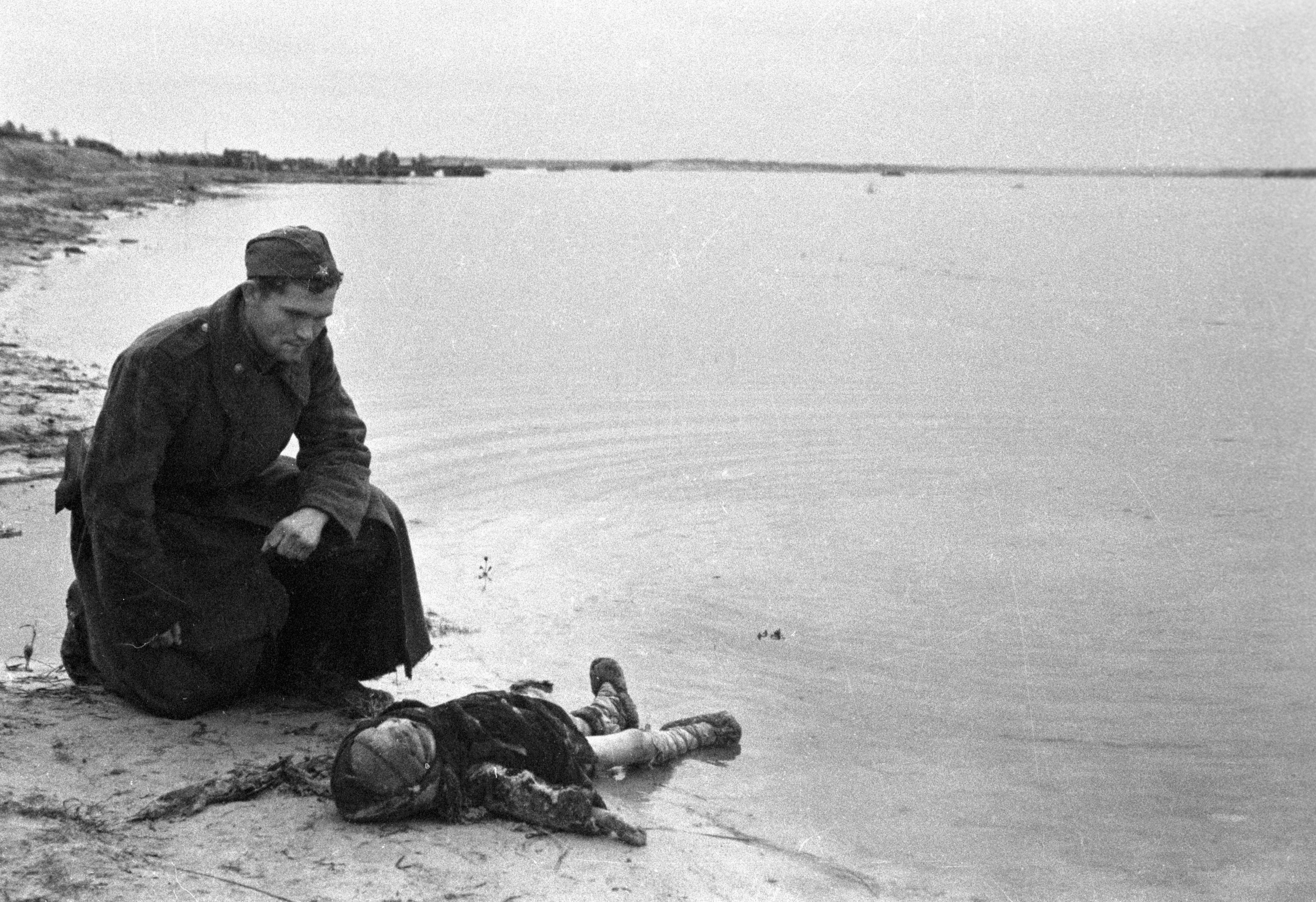 Советский солдат на берегу Днепра скорбит над убитым ребенком. Октябрь 1943 года